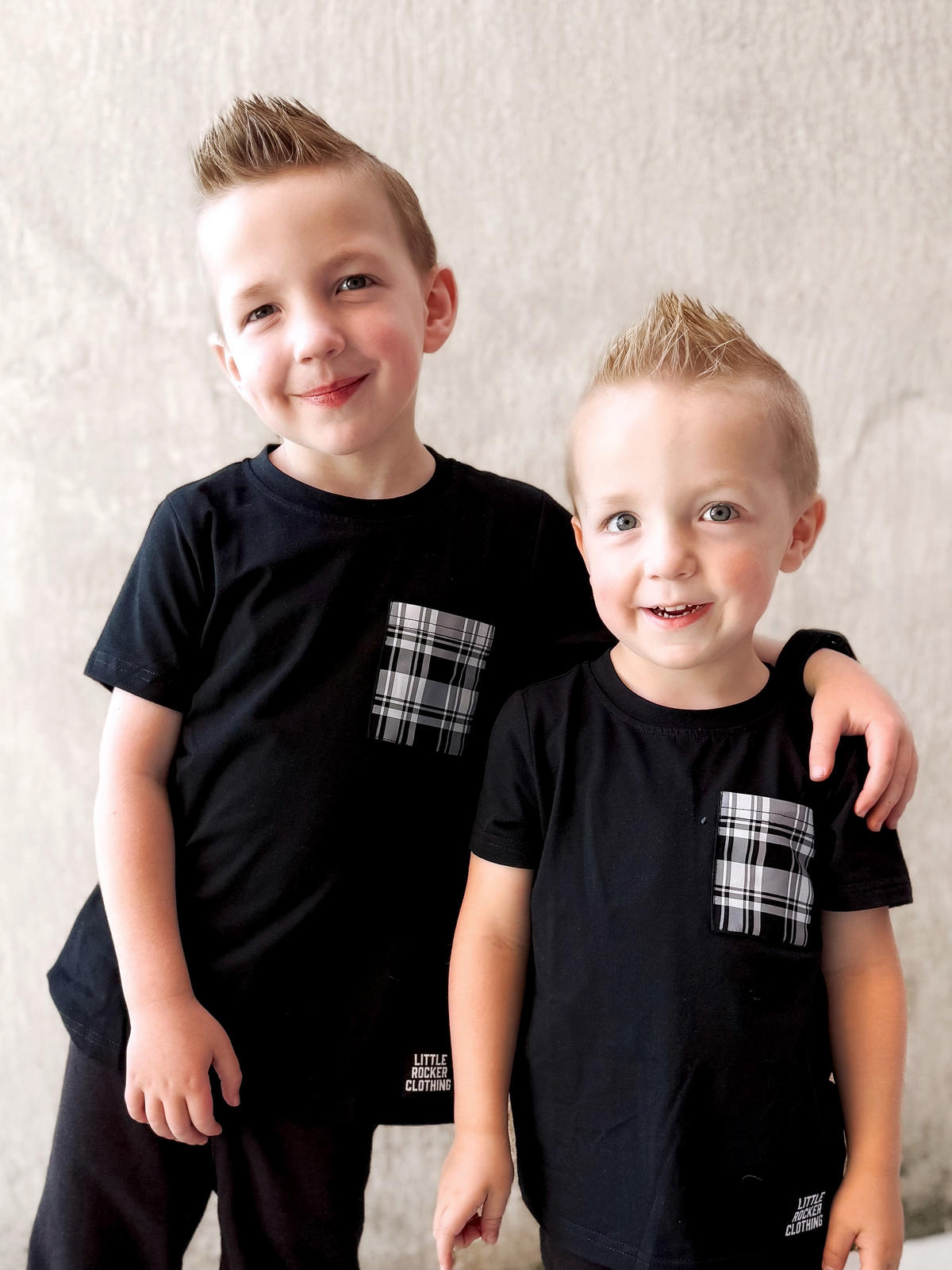 two boys wearing black tshirts with plaid pattern pockets