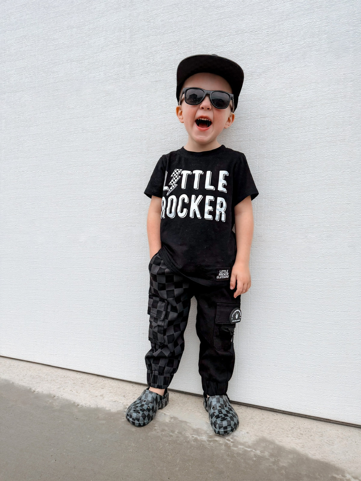 young boy matching his little rocker clothing shirt with kids half black half checkered cargo joggers black streetwear pants with cargo pockets rocker style toddler to youth sizes little rocker clothing