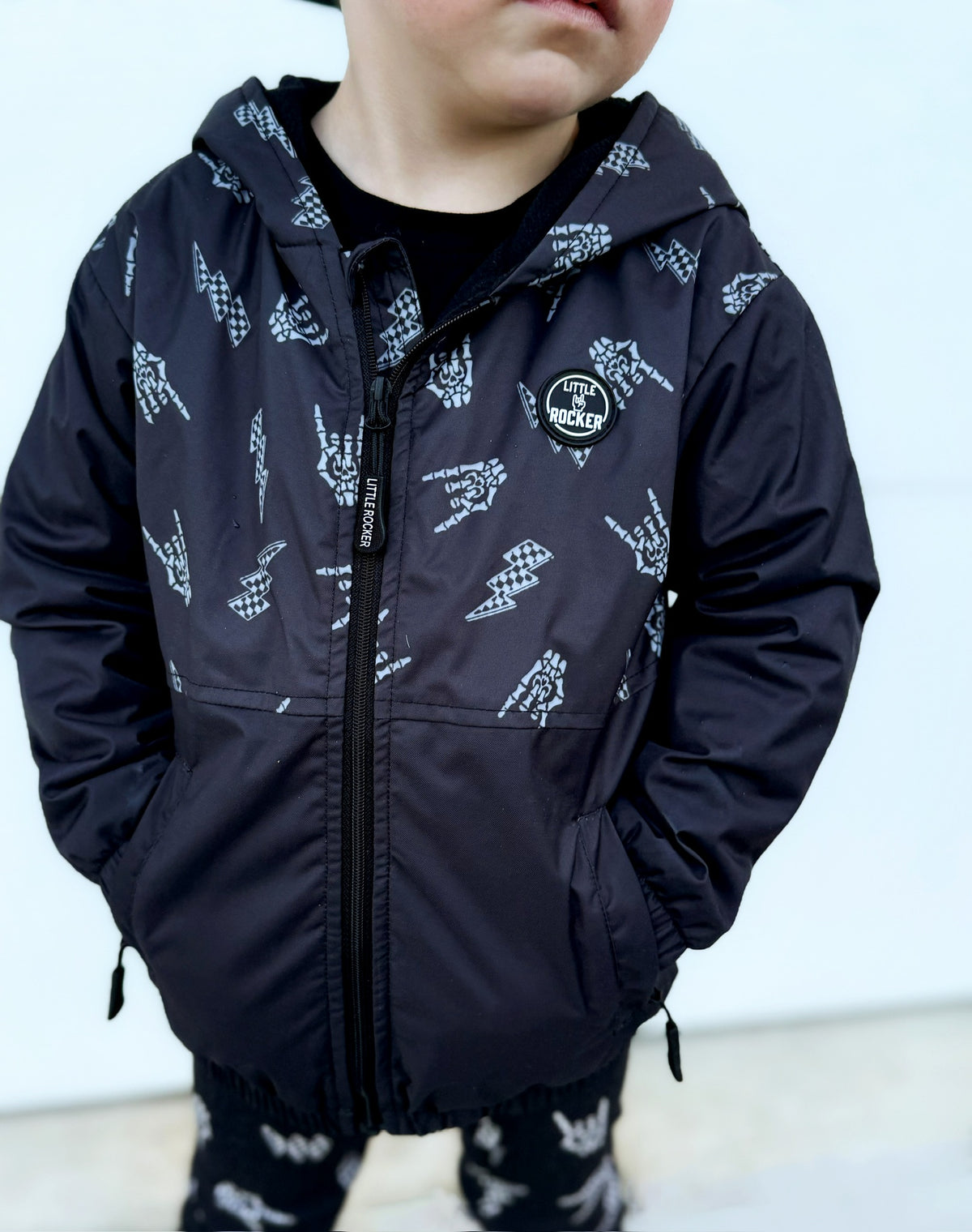 Close up of Kids bolted bones black windbreaker jacket with all over graphic print, lightweight rocker style outerwear for kids with zip front and hood