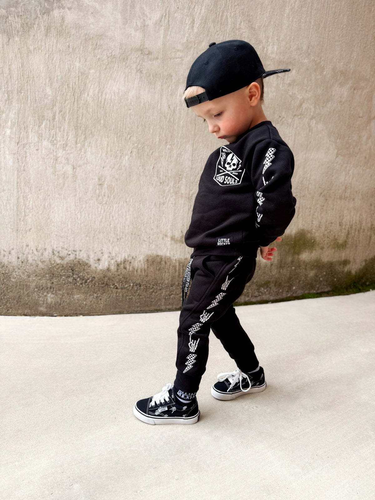 young boy wearing mom and sons wearing matching black aftershock crew neck sweatshirts and joggers set lightning bolt and rock hand print little rocker clothing adult and kids outfits