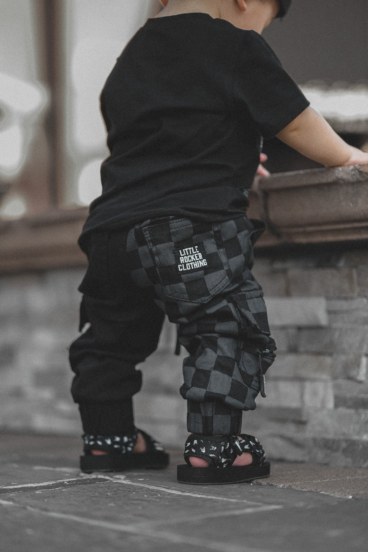 infant wearing kids half black half checkered cargo joggers black streetwear pants with cargo pockets rocker style toddler to youth sizes little rocker clothing
