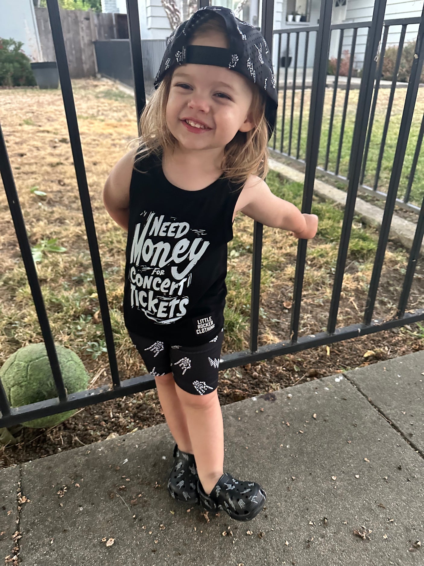 Girl outside playing in the kids graphic tank top that says need money for concert tickets black rocker style sleeveless shirt for kids summer outfit sizes toddler to youth