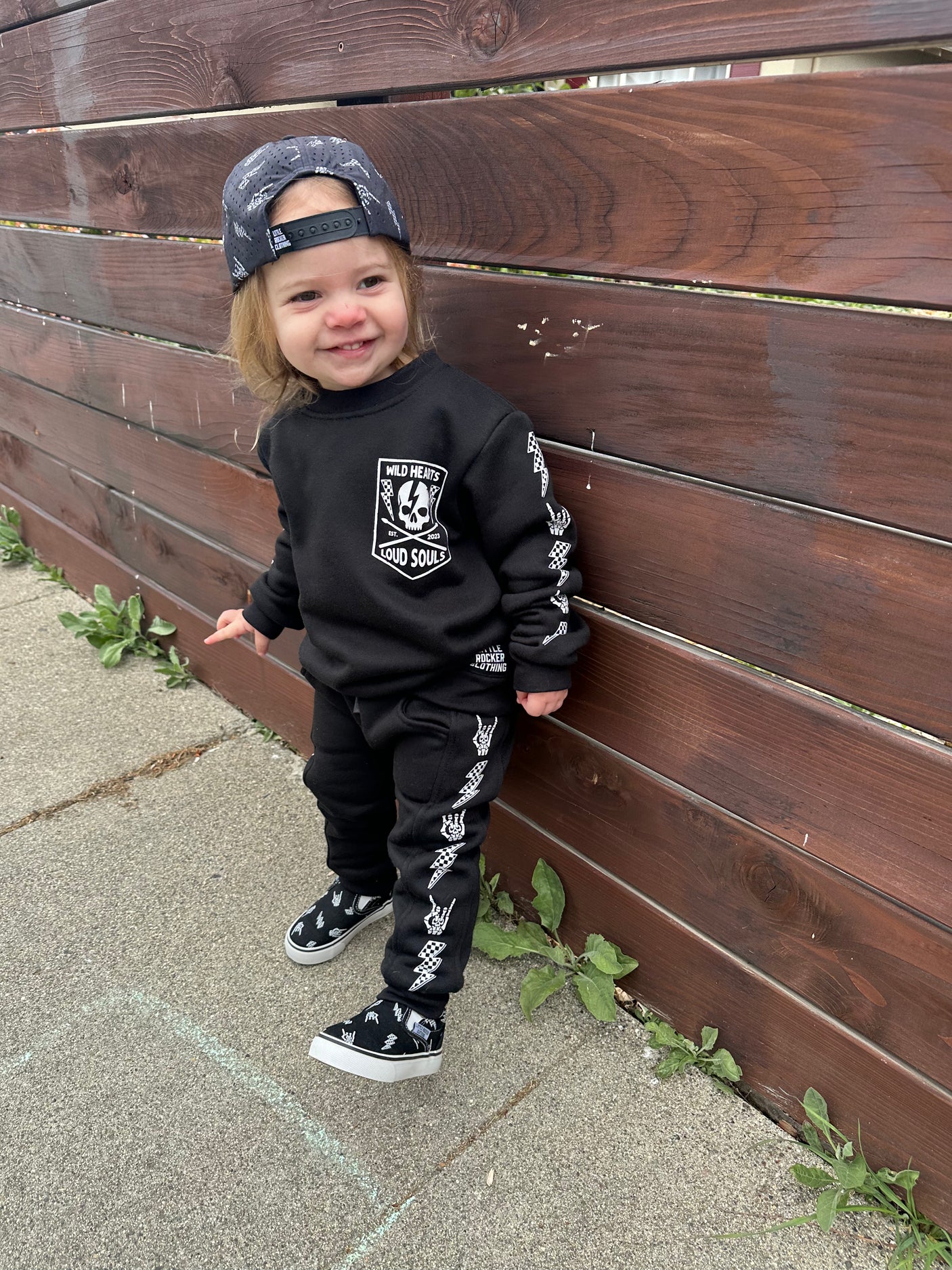 toddler girl wearing matching black aftershock crew neck sweatshirts and joggers set lightning bolt and rock hand print little rocker clothing adult and kids outfits