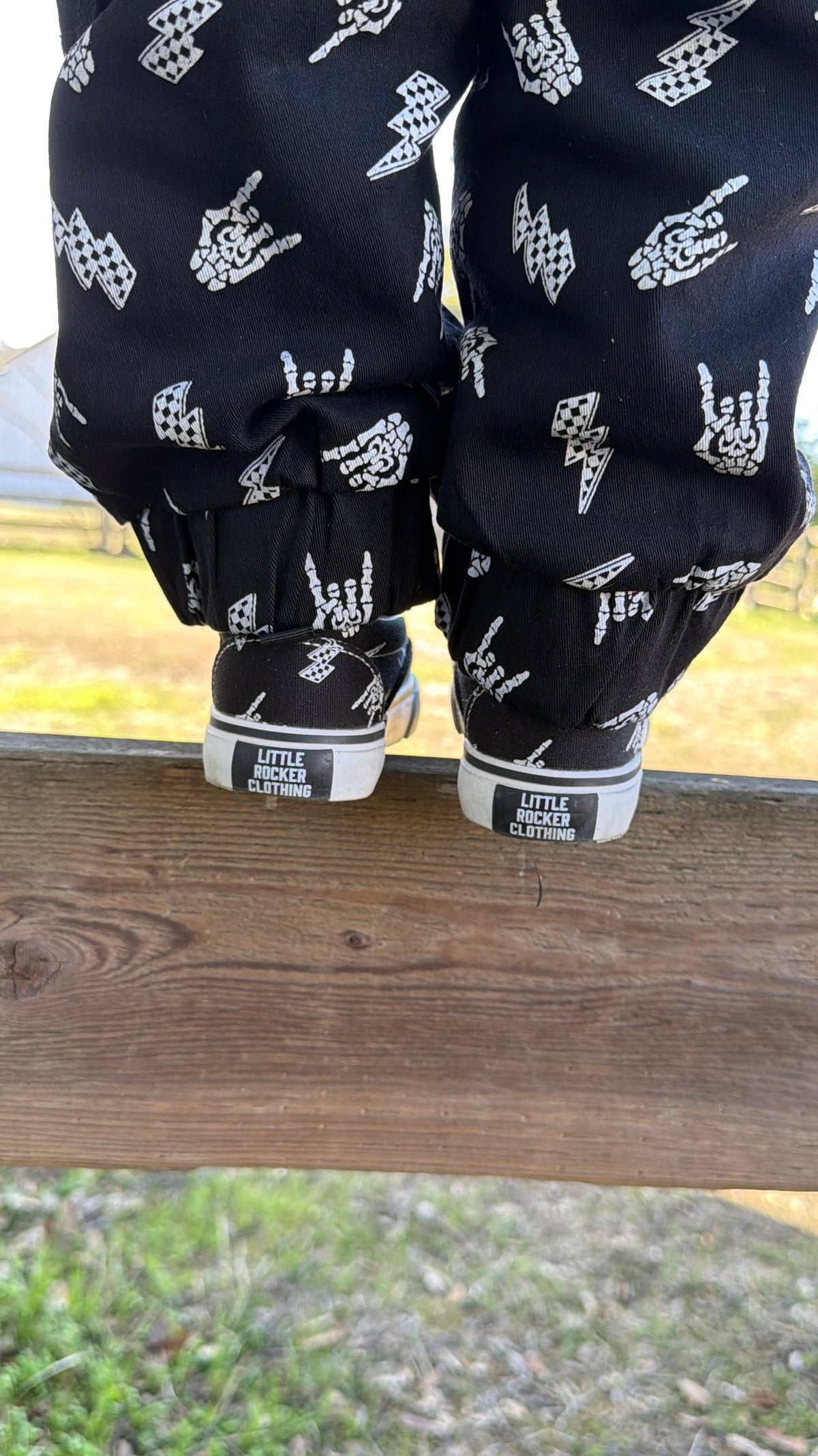 bolted bones canvas slip on shoes for kids with black and white skull and lightening bolt pattern, rocker style kids sneakers, elastic slip on design, little rocker clothing footwear back side with rubber emblem