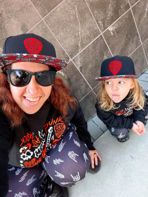 Kid and adult wearing Little Rocker Clothing black and red Scene Sampler snapback hat featuring bold music inspired design, adjustable snapback cap for kids and adults, edgy rock style apparel accessory