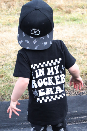 black kids graphic t-shirt with in my rocker era checkerboard detail, little rocker clothing rock style outfit for toddlers and kids outdoors rear view