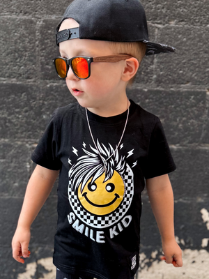 toddler boy wearing black kids graphic t-shirt with yellow smiley and smile kid, little rocker clothing rock style outfit for toddlers and kids 