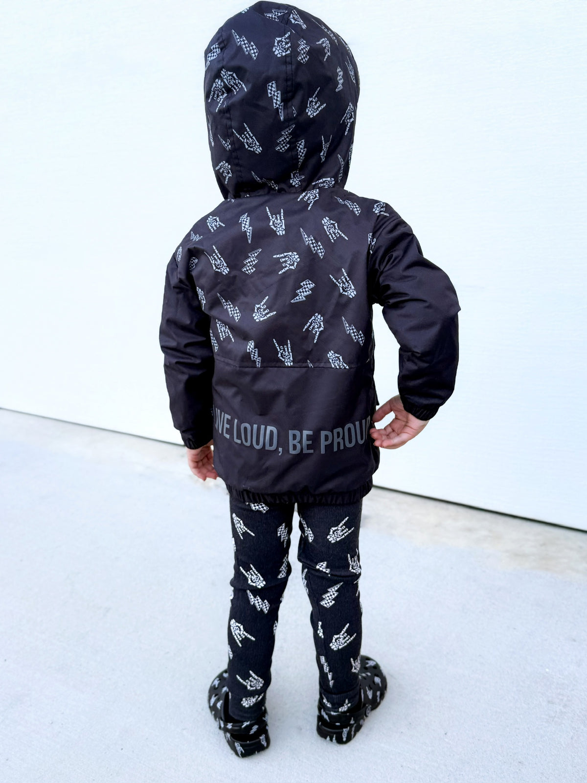 Kids bolted bones black windbreaker jacket with all over graphic print, live loud be proud on back side of the lightweight rocker style outerwear for kids with zip front and hood