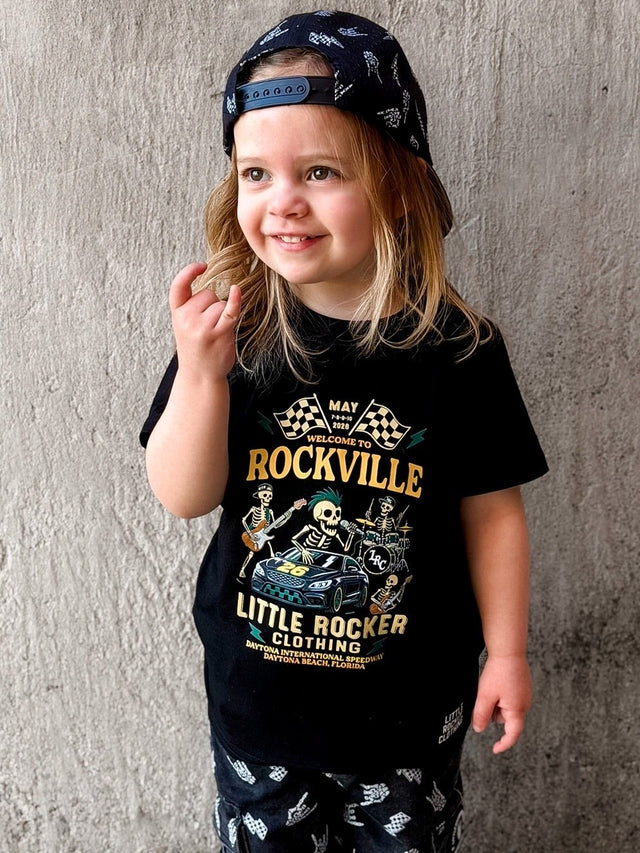 Girl wearing the official welcome to rockville kids graphic tee collaboration, rock festival band style t shirt for kids, black rocker tee with bold music design, little rocker clothing festival apparel