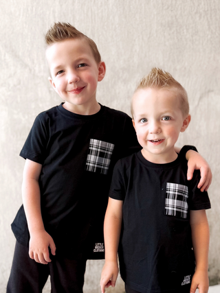 two boys wearing black tshirts with plaid pattern pockets