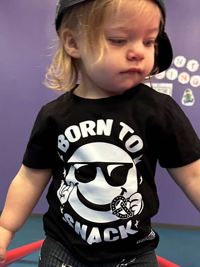 infant girl wearing black kids graphic t-shirt with born to snack text, little rocker clothing rock style outfit 