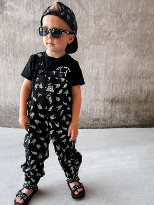 boy wearing kids black bolted bones overalls with lightning bolt and rock hand print matching outfits toddler streetwear little rocker clothing