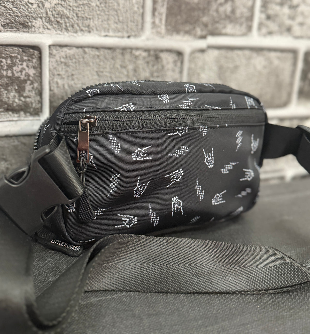 Little Rocker Clothing black Bolted Bones crossbody bag featuring signature skull bolt pattern, adjustable strap crossbody purse with compact functional design, edgy rock style accessory for concert festivals