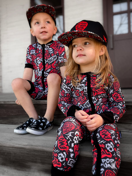 Black and Red baby pajamas featuring an edgy rock-inspired print, made from ultra-soft breathable fabric, designed for babies and toddlers up to size 5T with a comfy stretchy fit and short sleeves and short pant legs for warmer nights paired with a rock inspired snapback. 