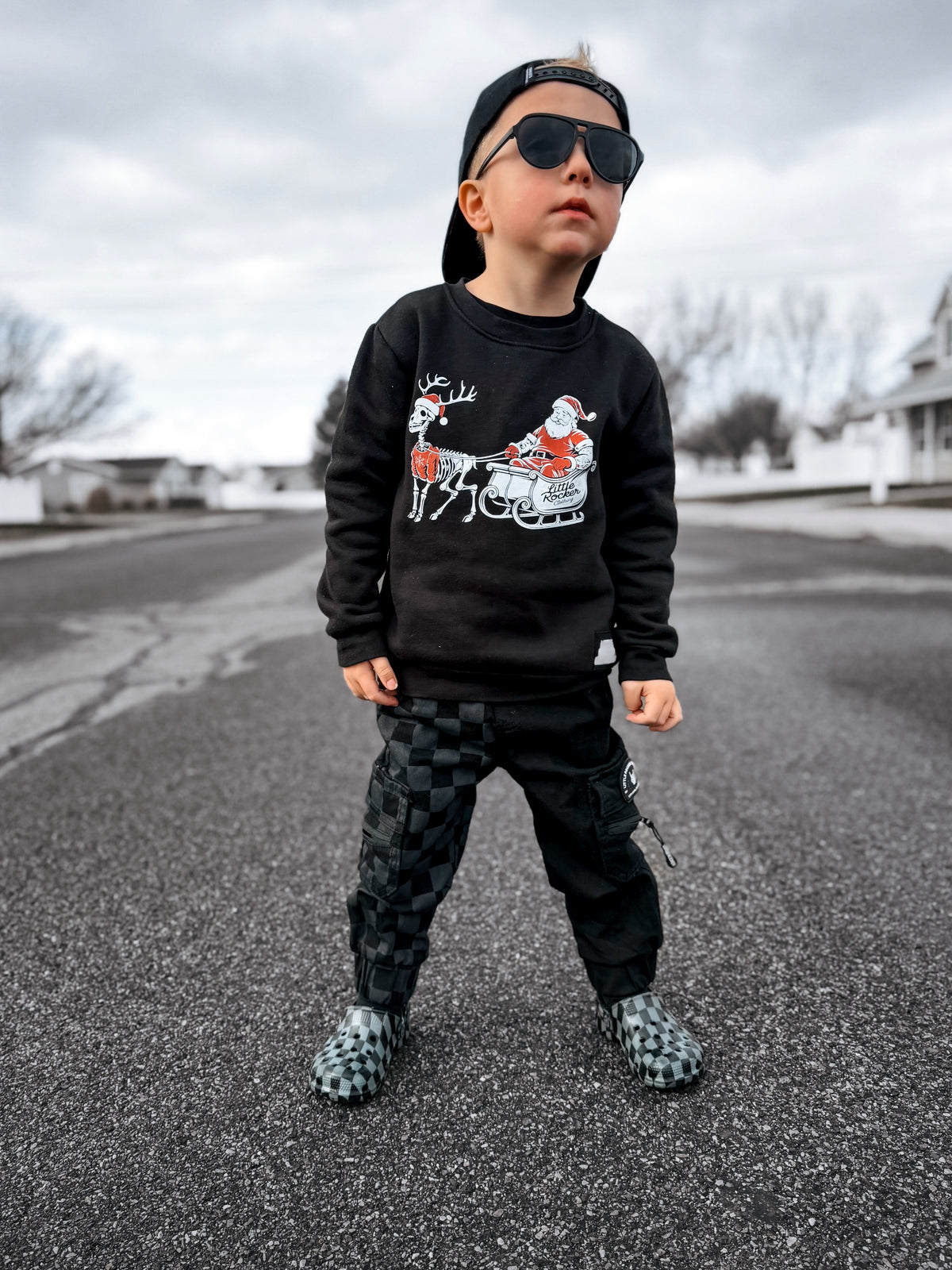 boy in the little rocker clothing christmas crew neck and kids half black half checkered cargo joggers black streetwear pants with cargo pockets rocker style toddler to youth sizes little rocker clothing