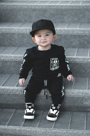 infant wearing matching black aftershock crew neck sweatshirts and joggers set lightning bolt and rock hand print little rocker clothing adult and kids outfits