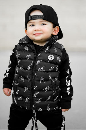 Infant wearing Kids black puffer vest with Bolted Bones design featuring skeleton hand rock on graphic and lightning bolts, rocker style outerwear for kids