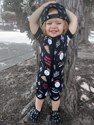 toddler wearing pop punk collage pattern short sleeve zip up bamboo pajamas for kids paired with black snapback