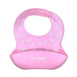 A pink silicone baby bib with a chin cup, featuring a white pattern of small boats on the upper portion and a white 'LITTLE ROCKER' brand label on the lower cup, displayed flat on a light wood grain background.