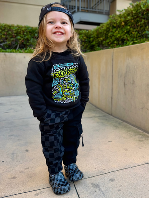 girl wearing the kids half black half checkered cargo joggers black streetwear pants with cargo pockets rocker style toddler to youth sizes little rocker clothing