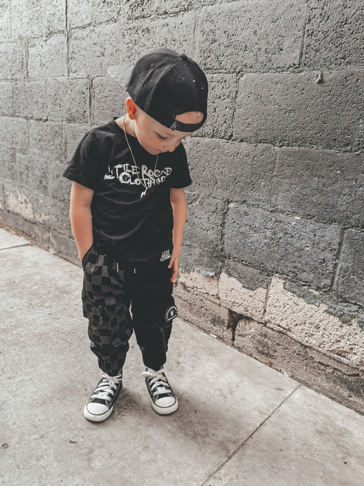young boy sporting streetwear kids half black half checkered cargo joggers black streetwear pants with cargo pockets rocker style toddler to youth sizes little rocker clothing