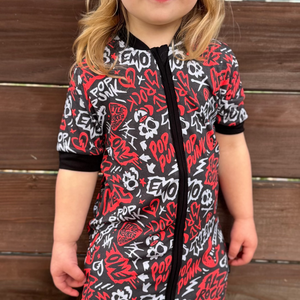 Black and Red baby pajamas featuring an edgy rock-inspired print, made from ultra-soft breathable fabric, designed for babies and toddlers up to size 5T with a comfy stretchy fit and short sleeves and short pant legs for warmer nights paired with a rock inspired snapback. 
