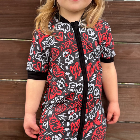 Black and Red baby pajamas featuring an edgy rock-inspired print, made from ultra-soft breathable fabric, designed for babies and toddlers up to size 5T with a comfy stretchy fit and short sleeves and short pant legs for warmer nights paired with a rock inspired snapback. 