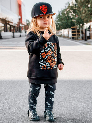 Toddler giving the rock on horns is wearing the scene sampler crew neck sweatshirt for kids and adults with pop punk alt rock metal emo graphic design, rocker style apparel, little rocker clothing