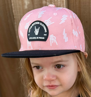 Kid wearing pink and black rock on and lightening bolt snapback hat, adjustable snapback cap for kids and adults, edgy music inspired apparel accessory