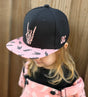 Kid wearing Little Rocker Clothing pink and black rock on snapback hat, adjustable snapback cap for kids and adults, edgy music inspired apparel accessory