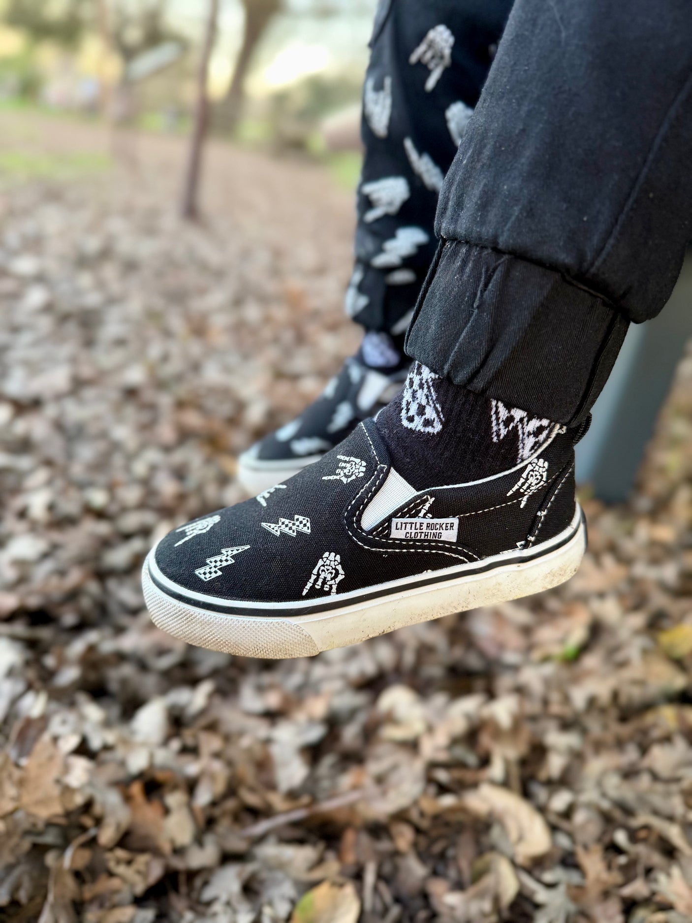 bolted bones canvas slip on shoes for kids with black and white skull and lightening bolt pattern, rocker style kids sneakers, elastic slip on design, little rocker clothing footwear
