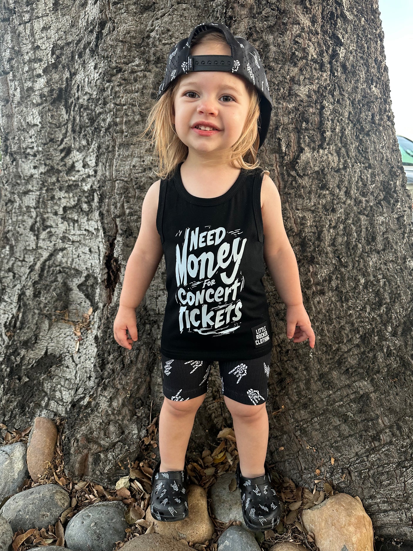 Toddler wearing kids graphic tank top that says need money for concert tickets black rocker style sleeveless shirt for kids summer outfit sizes toddler to youth