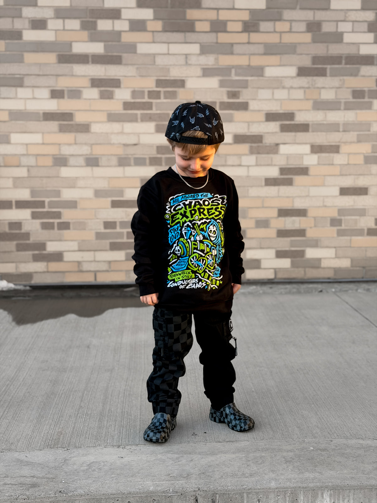 Lifestyle image of Kids black Scene Sampler crew neck sweatshirt featuring pop punk, emo, and alt rock graphic with train illustration, rocker style kids apparel