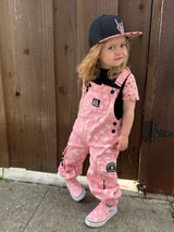 child wearing pink bolted bones overalls from little rocker clothing and pink and black snapback