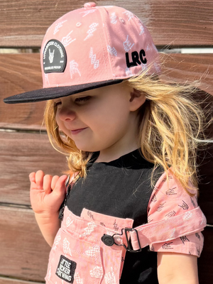 Kid wearing pink and black rock on and lightening bolt snapback hat, adjustable snapback cap for kids and adults, edgy music inspired apparel accessory