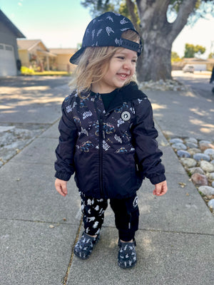 Toddler girl playing in Kids Beast Mode black windbreaker jacket with all over graphic print, lightweight rocker style outerwear for kids with zip front and hood