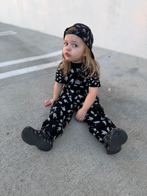 girl wearing kids black bolted bones overalls with lightning bolt and rock hand print matching outfits toddler streetwear little rocker clothing