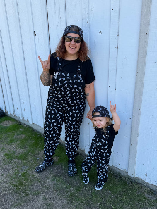 adult wearing black bolted bones overalls with matching kids outfit styled as edgy alternative clothing from Little Rocker Clothing