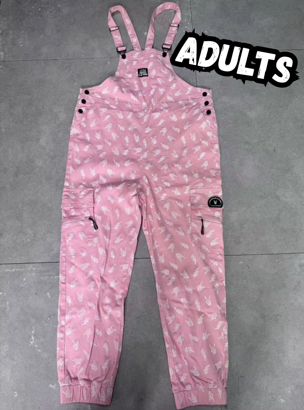 lay flat pink adult overalls with rock on hands and lightening bolts 
