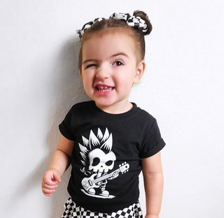 black kids graphic t-shirt with skeleton with a mohawk playing the guitar,  little rocker clothing rock style outfit for toddlers and kids outdoors rear view