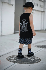 child wearing backwards snapback hat, drumming skeleton tank top and checkered shorts from little rocker clothing