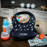 A black silicone baby bib with a white hand-drawn rocker style pattern for punk and rocker parents